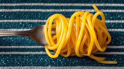 Spaghetti noodles twirled on a silver fork against a striped teal and white patterned background cloth