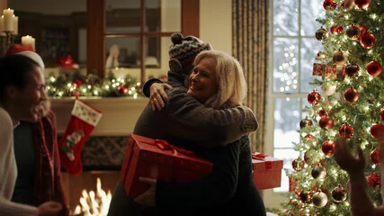 Older caucasian couple in winter coats enter a cozy christmas living room, warmly embracing diverse family amidst golden light, tree, and gifts. Heartwarming family reunion joy