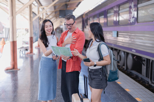 Group of diverse friends standing on a train station platform, holding a map, discussing travel plans, expressing happiness and surprise before their journey