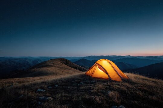 Camping under a starlit sky in a peaceful mountain setting showcasing a glowing tent near the edge of a highland at twilight