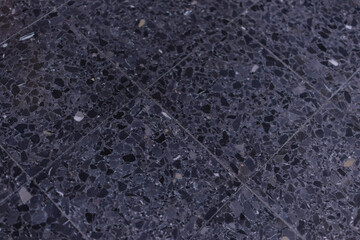 Gray terrazzo floor showcasing a speckled pattern of various chipped stone fragments embedded in polished cement, forming a durable and decorative surface