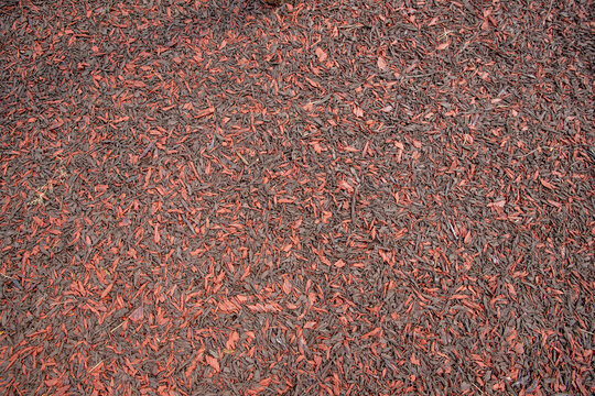 rubber coating of run track, playground or sports ground texture background. Rubber mulch imitating wood chips, shavings, fractions 12-50 mm. red brown Rubber Playground Surfacing, sports grounds.
