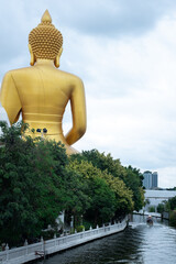 A big Buddha and small boat at canal line