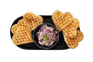 Heart-shaped waffles and red cabbage salad served on a black plate. The waffles are golden brown and perfectly shaped, accompanied by a vibrant, appetizing salad