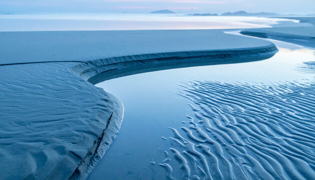 Serene beach landscape with a winding stream at dusk.