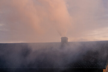 A smoking chimney against a sky background.