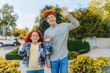 Redhead Teenagers Smiling and Waving Hello Gesture Outdoors in City