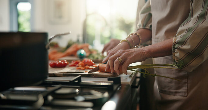 Cooking, cutting and hands with old person in kitchen of home for healthy meal preparation. Busy, food and knife with senior woman chopping vegetables at counter in apartment for hunger or recipe