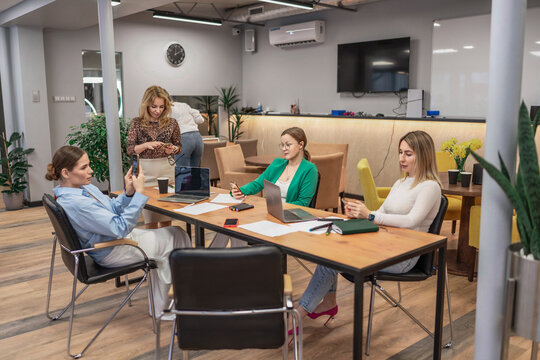 Businesswomen team meeting in modern office lounge area collaborating using laptops and smartphones - Powered by Adobe