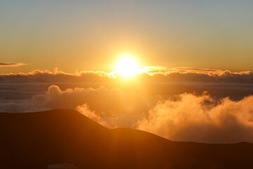 Intense golden sun setting into thick swirling mountain clouds