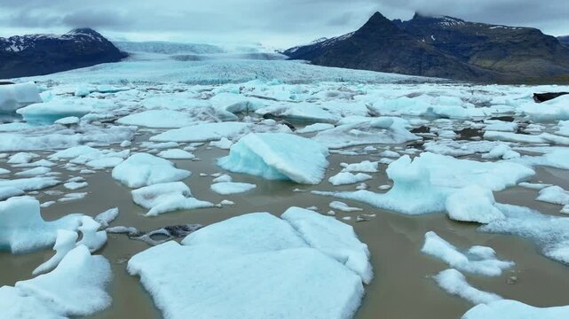 Vatnajokull : Floating icebergs melting in a glacial lagoon with majestic mountains in the background