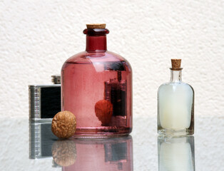 Still life with homemade fruit juice in vintage color bottles and walnuts on a glass top table