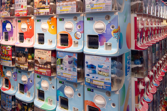 Tokyo, Japan - March 14, 2025: Japanes woman with mouthcap in Illuminated shop with Japanese Gashapon in Tokyo, Japan. Gachapon are vending machines that dispense capsuled toys.