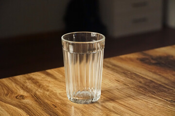 An empty glass made of rough glass stands on the table