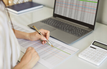 Online stock calculating, accounting monthly expenses, managing company budget, entering data in computer application, sitting at table making notes in paper documents, businesses and corporations