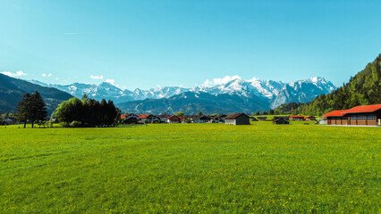 Obraz premium Lush field with rustic cabins and Alps