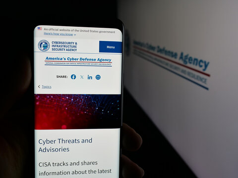 Stuttgart, Germany - 11-02-2025: Person holding smartphone with web page of cyber security and infrastructure agency CISA on screen in front of logo. Focus on center of phone display.