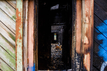 Eerie view inside a fire-ravaged home, revealing widespread charring, debris, and structural devastation. The grim aftermath of a disaster, hinting at past life
