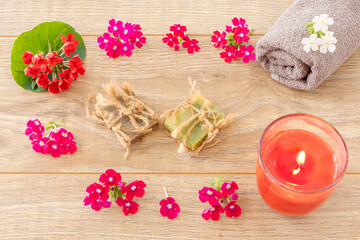 Towel with body care products and verbena flowers on the wooden background.
