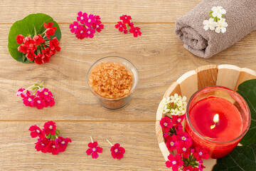 Towel with body care products and verbena flowers on the wooden background.