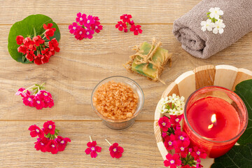 Towel with body care products and verbena flowers on the wooden background.