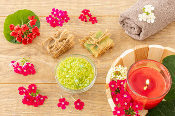 Towel with body care products and verbena flowers on the wooden background.