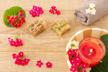 Towel with body care products and verbena flowers on the wooden background.