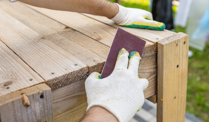 Tools for sanding wood. Carpenter sanding wooden plank on table, closeup. Sanding wood with sandpaper.