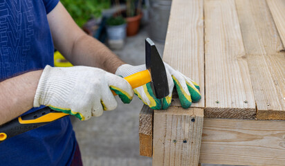 Close-up. Carpenter with hammer and nails fixes a wooden board. Construction industry, do it yourself. Wooden work table.