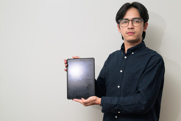 Portrait of handsome young Asian Thai man wearing eyeglasses using digital tablet computer
