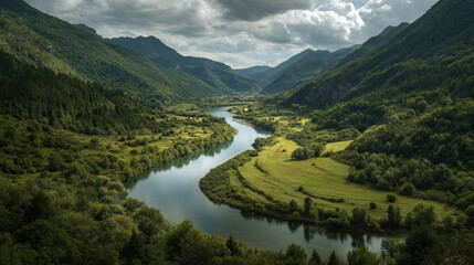 Aerial view of a winding river flowing through a lush green valley with mountains