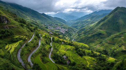 Fototapeta premium Aerial view of lush green rice terraces and winding road under cloudy sky day