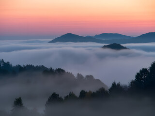 Obraz premium Scenic Mountain Landscape with Fog and Sunrise. Beautiful Nature View of Misty Hills and Colorful Sky at Dawn