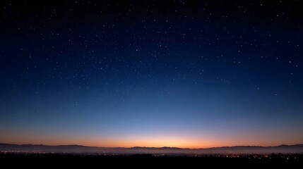 A serene twilight sky filled with stars glows above a distant silhouetted cityscape and mountain range