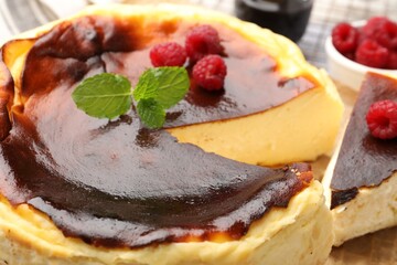 Tasty Basque cheesecake with raspberries and mint on table, closeup