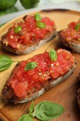Tasty bruschettas with tomatoes and basil on table, closeup