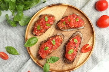 Tasty bruschettas with tomatoes and basil on white table, flat lay