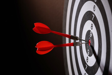 Dartboard with darts on black background, closeup
