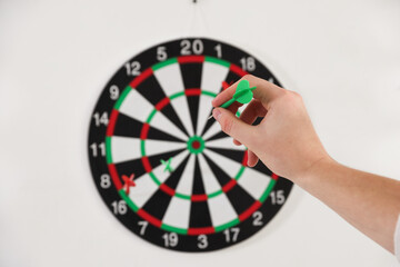 Obraz premium Man with dart aiming at dartboard indoors, selective focus