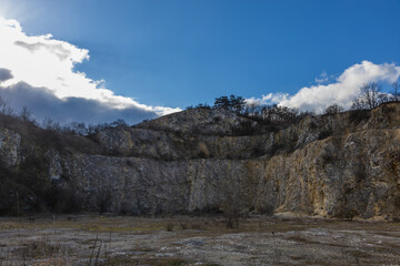 Geological structure of an abandoned limestone quarry under a blue sky