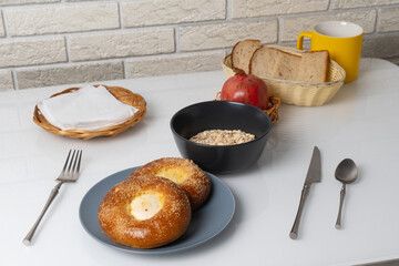 Fresh breakfast spread featuring buns, oats, and a pomegranate in a cozy kitchen setting