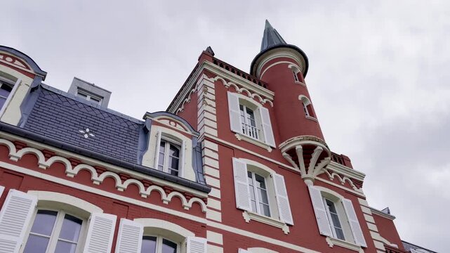 Le Crotoy, France - October 17 2024 : Iconic red brick building of the Hotel Les Tourelles, Somme Bay, featuring elegant white shutters, green pointed turrets and classic seaside architecture