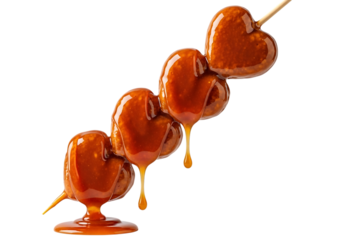 Four delicious heart shaped candies covered in caramel drizzle isolated on transparent background