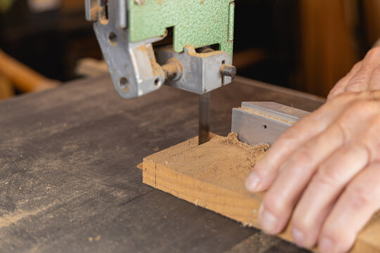 Plan serr&eacute; sur les mains d&rsquo;un menuisier guidant le bois sur la scie.