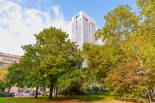 Frankfurt, Germany - October 21, 2025: Modern Skyscraper Towering Over Autumnal Park in Frankfurt