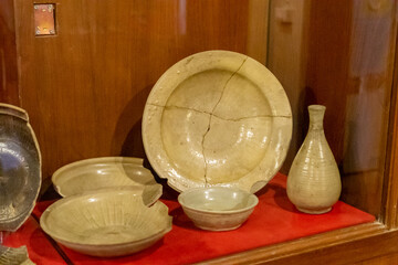 Old ceramic bowl with hand-painted fish motif from Thailand, displayed in a museum. Traditional antique pottery showing ancient craftsmanship and cultural heritage.