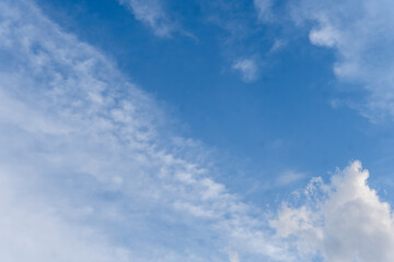 A clear blue sky background with layers of thin, wispy cirrus and altocumulus clouds. A bright, sunny day scene representing good weather and serenity.
