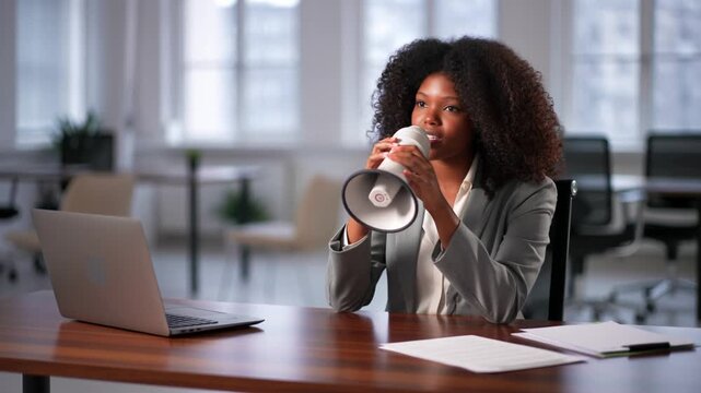 A woman in a business setting speaks into a megaphone, next to a laptop and papers, possibly giving a speech Stock Video