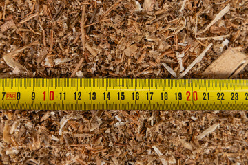 Un outil de mesure placé sur la sciure après un travail de menuiserie.