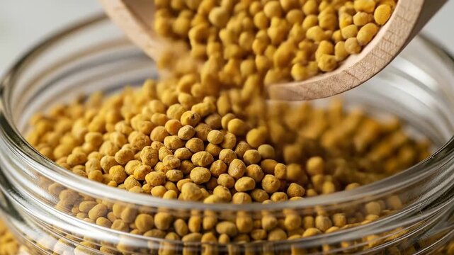 Healthy organic bee pollen granules being poured into a glass jar.